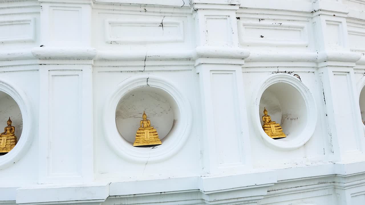 A serene view of Bangkok's Prayurawongsawat Temple, showcasing intricate white architecture and golden details under soft daylight
