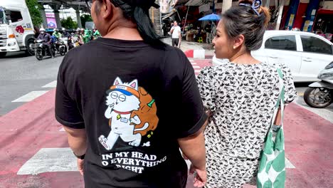 a couple navigates a crosswalk in bangkok