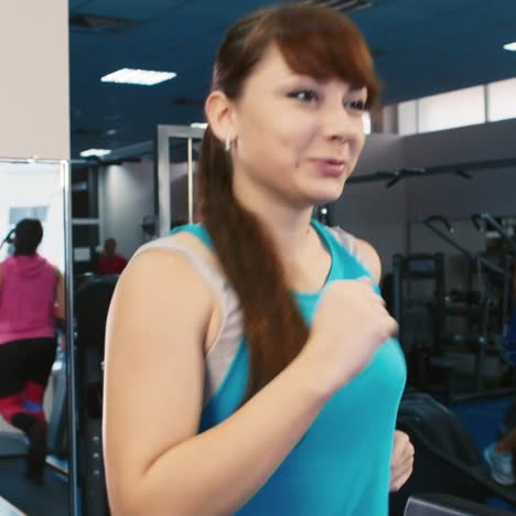 woman trains in the gym as other people train in the background 5