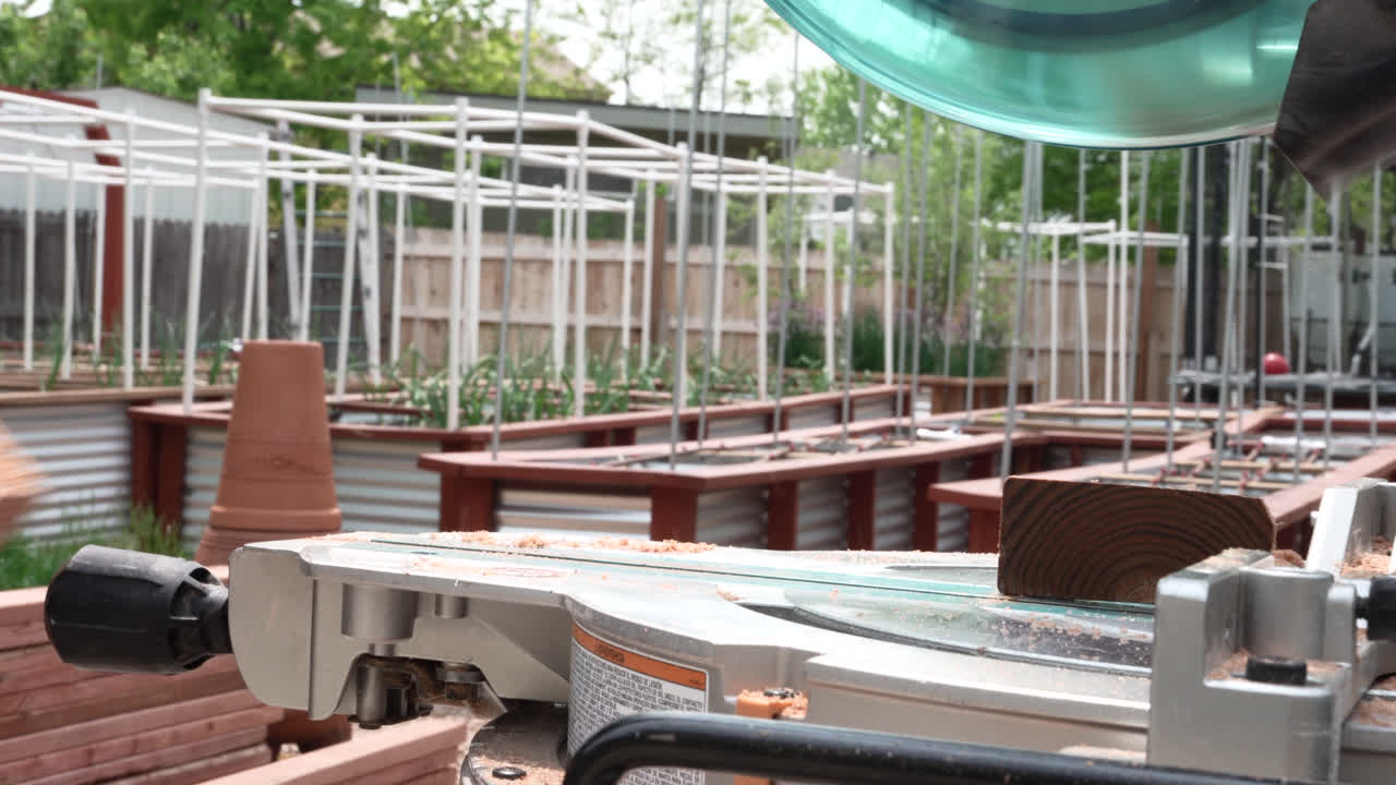 정원에서 현대 원형 사를 사용하여 나무의 판을 절단하는 사람