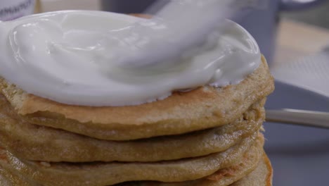 primer plano de colocar una cucharada de yogur en panqueques