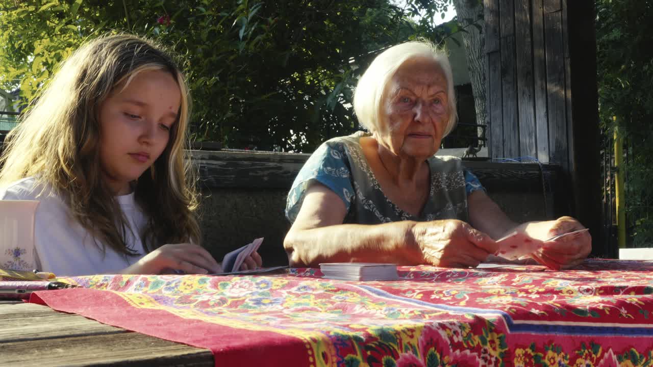 I bambini si divertono a giocare a carte con la nonna sotto il sole estivo