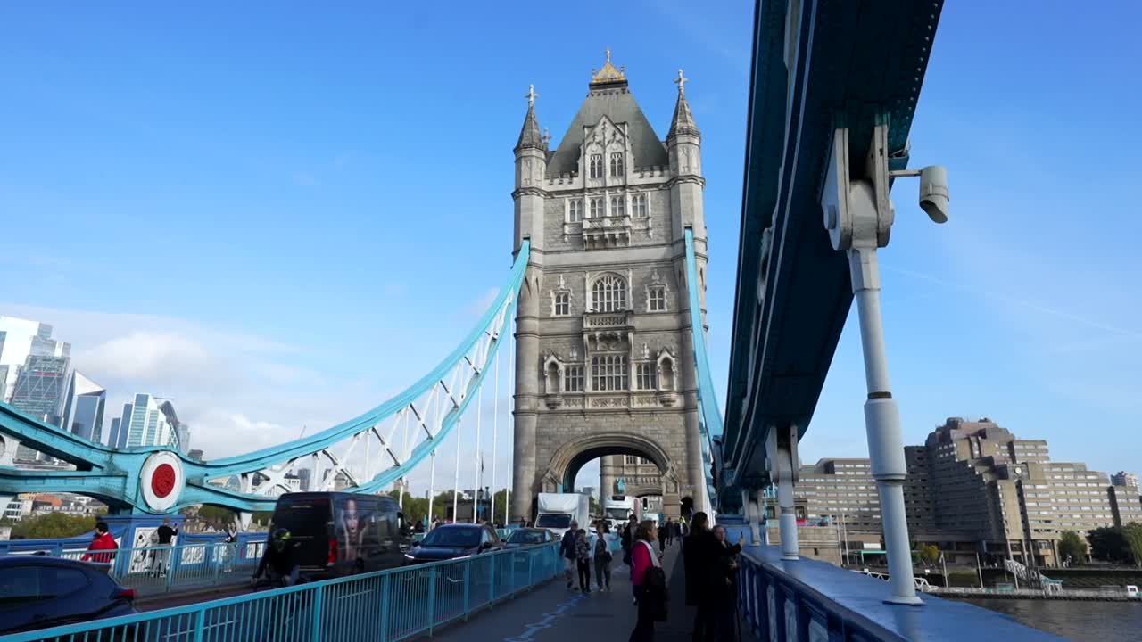Tourists and vehicles crossing London’s iconic Tower Bridge on a sunny day with clear skies