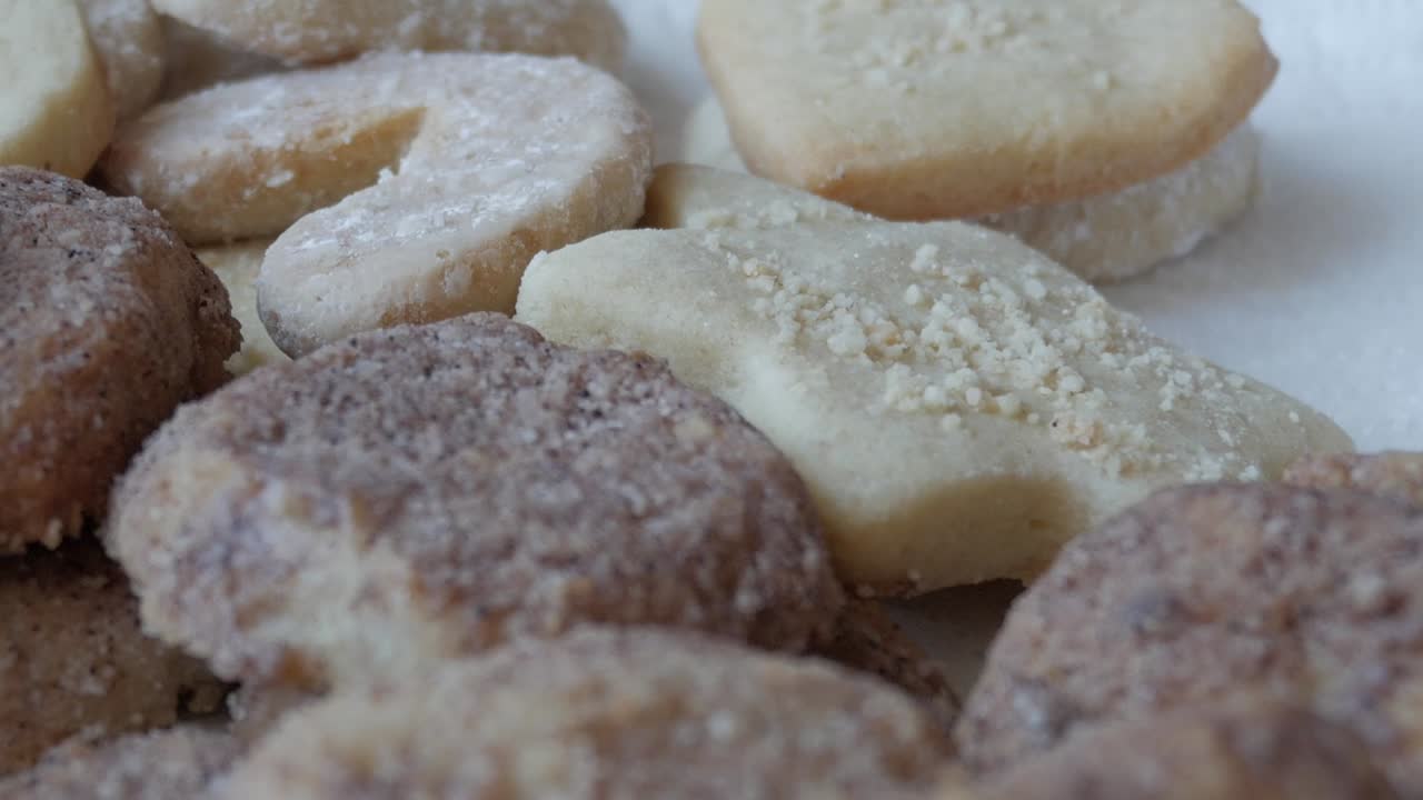 A close-up pan from upper left to bottom right, filling the frame with brown German Butterplätzchen cookies, capturing their crumbly texture and authentic, homemade appeal