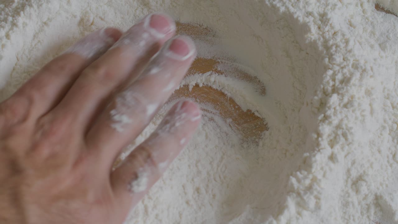 Close-Up of Hand Making Well in Flour on Kitchen Table
