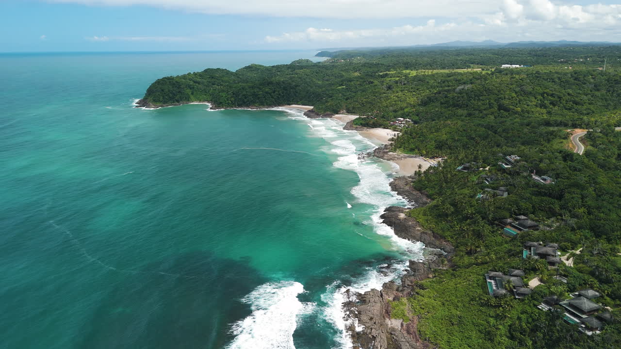 Drone ascends over four white sandy beaches, lush jungle, rocky coast, and blue ocean in Itacare, Bahia