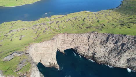 aerial tilt-up reveals lake sorvagsvatn above the ocean framed by towering cliffs
