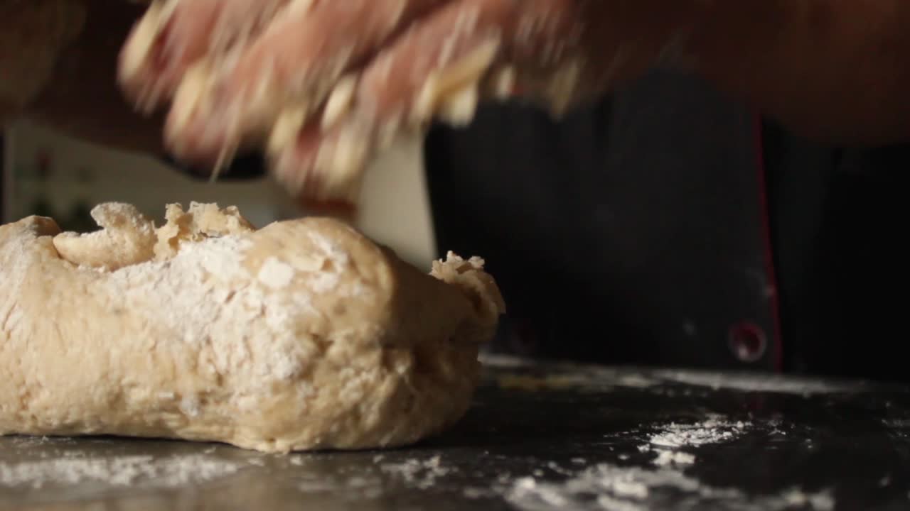 close up hands of female chef deflating pizza dough, restaurant kitchen