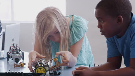dos estudiantes construyendo y programando un vehículo robot después de la clase de codificación de computadoras de la escuela