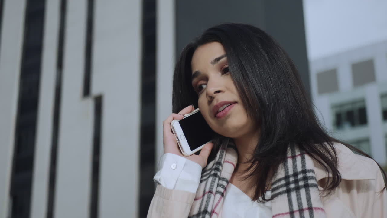 Businesswoman talking on smartphone at street. Employee using mobile phone