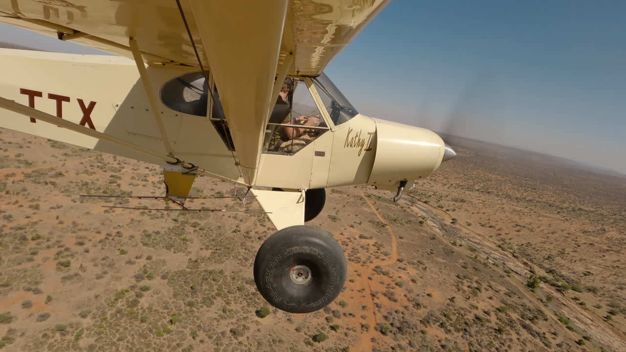Piccolo aereo leggero sopra il letto di un fiume asciutto in una pianura keniota