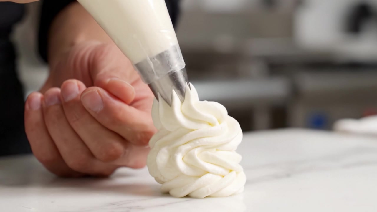 Dominando a Arte da Confeitaria com Bico: Uma Jornada Culinária Através de Espirais de Creme Lindamente Elaboradas sobre uma Superfície de Mármore