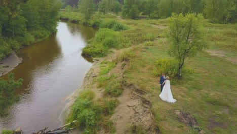 una joven pareja se une de manos en el río estrecho en la vista aérea de madera