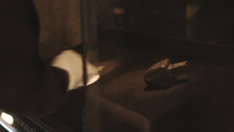 old historic archeological renaissance relics and figurines being taken from a glass showcase with white gloves in a museum. shot in 4k.