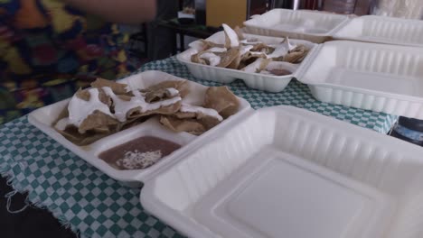 A-cook-pouring-sour-cream-and-cheese-on-green-chilaquiles