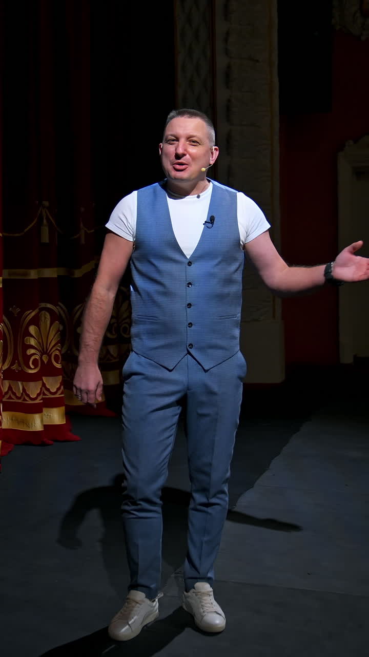 Man in front of empty theatre hall with red velvet chairs. Actor is standing on stage and talking with gestures before the performance. Vertical video