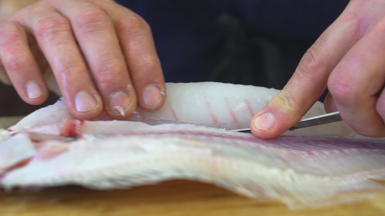 cuchillo deslizante a través del pescado para separar los filetes