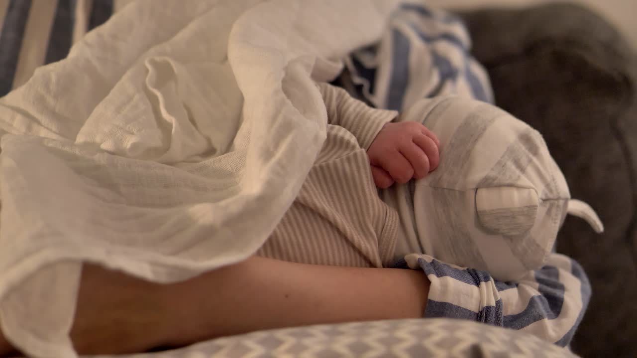 Madre che tiene delicatamente in braccio un neonato, primo piano della tenera manina del bambino