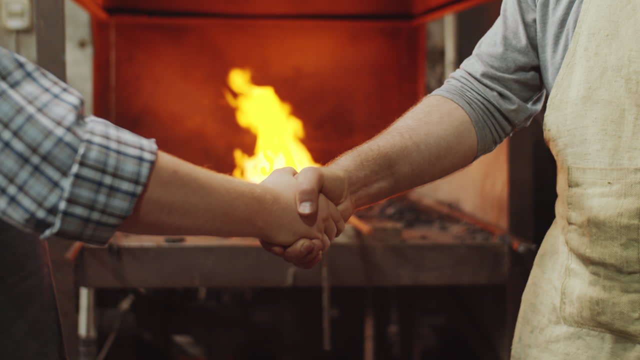 dos herreros dándose la mano y golpeando los puños en el trabajo