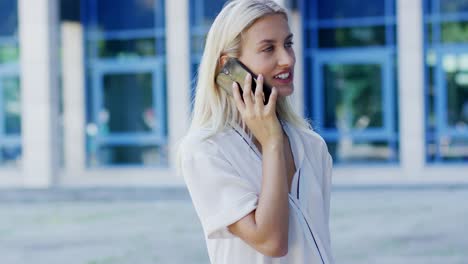 young woman speaking on phone near building