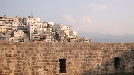 old-town-and-mountains-beyond-an-ancient-stone-castle-wall-in-Tripoli,-Northern-Lebanon