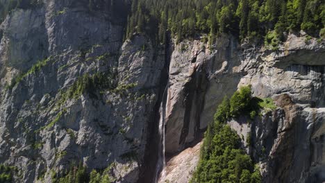 waterfall rocky cliff swiss alps mountain side forest covered, switzerland