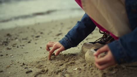 petit enfant dessinant du sable sur la plage de l'océan. mains d'enfant jouant sur le rivage à l'extérieur