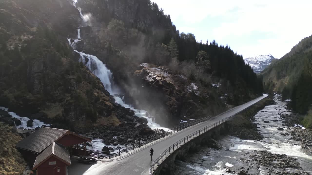Drone shot of male tourist walking on bridge under the Latefoss waterfall, Norway