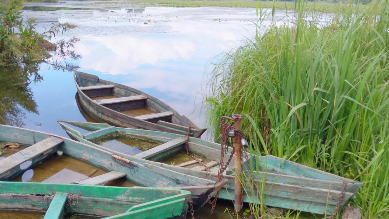 panorama vertical de un paisaje idílico con barcos de pesca abandonados en un río o estanque, lago. lugar ideal para la actividad de ocio de jubilación. imágenes de video 4k uhd