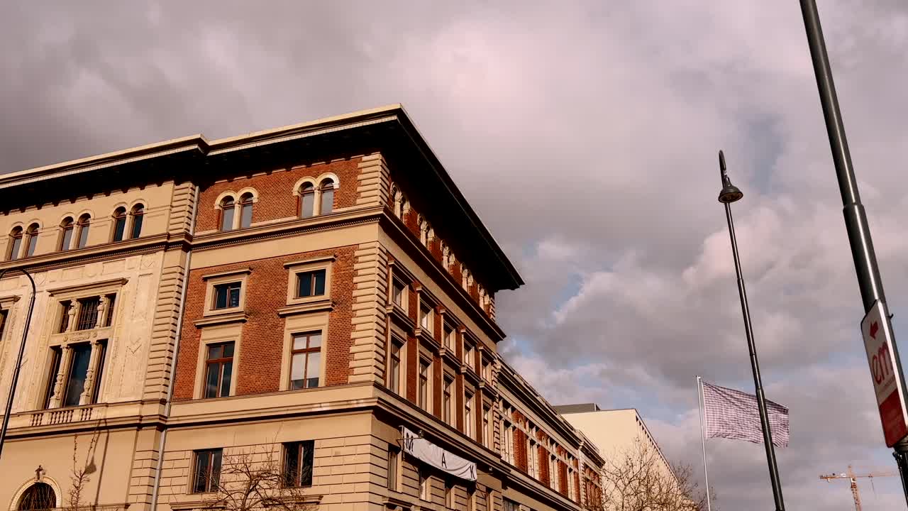 historic brick and stone building under a cloudy sky with a waving flag in Vienna, Austria