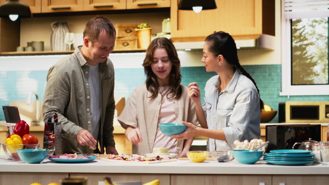 Parents and tween sprinkling mozzarella and grated cheese on homemade pizza