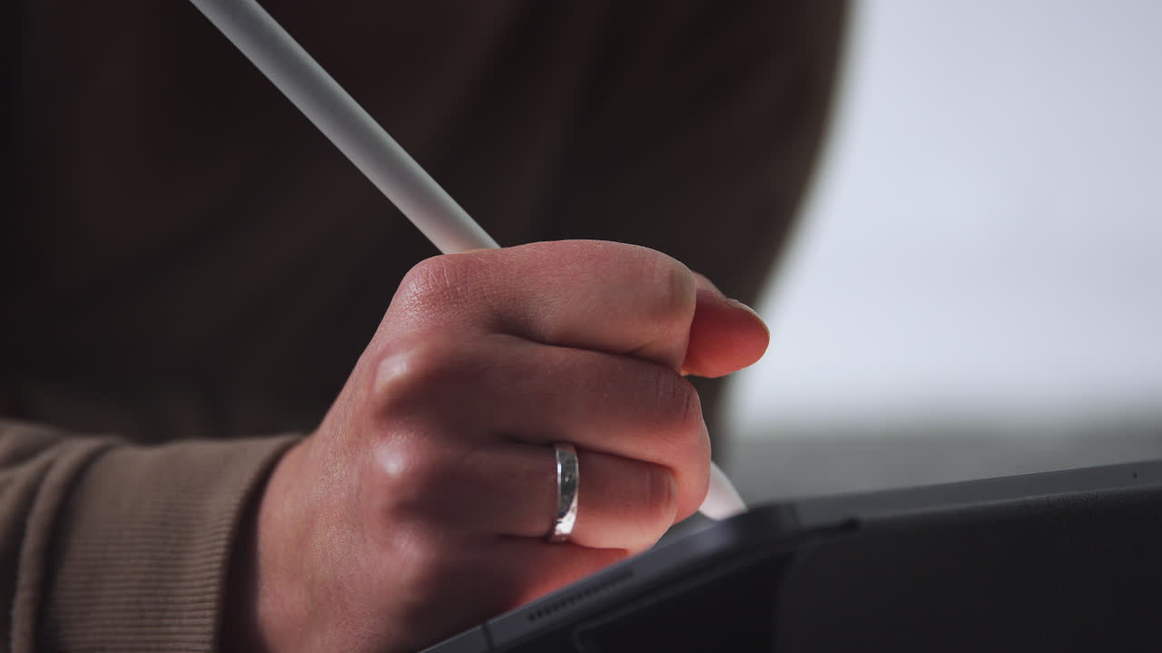 밤에 스타일러스 펜을 사용하여 디지털 태블릿에 그림을 그리는 여성의 클로즈업