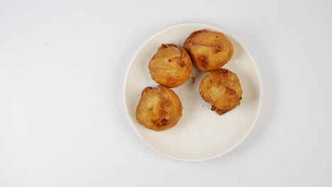 hand reaching for a plate of fried indian snacks