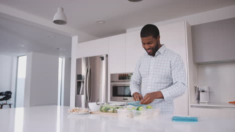 Man-In-Kitchen-Preparing-High-Protein-Meal-And-Putting-Portions-Into-Plastic-Containers