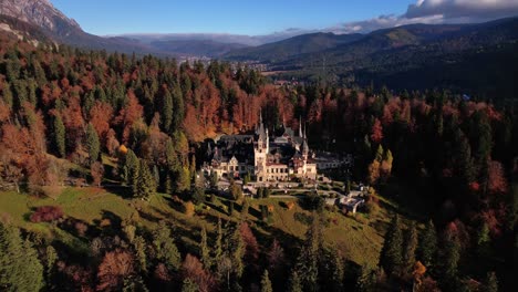 autumnal aerial view of peles castle amidst colorful trees in daylight