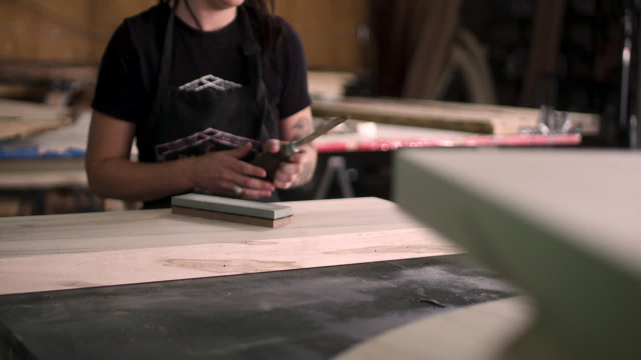 Craftswoman Grabbing A Chisel To Use On A Small Wooden Block In A Wood Working Studio In London, Ontario, Canada - Medium Shot Slow Motion 4k 60p