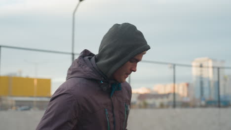 focused athlete training with soccer ball in sport arena, showcasing skills in dynamic movement against blurred background of urban buildings and goalpost