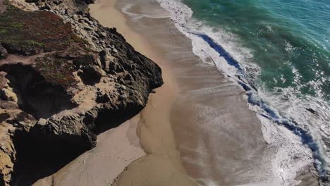 Waves-swirling-on-sunny-rocky-coastal-beach-during-late-afternoon