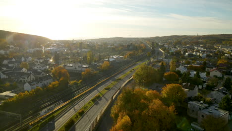 volando de regreso a lo largo de la sinuosa carretera y la vía férrea en color otoñal gdynia cityskyline en un brillante amanecer