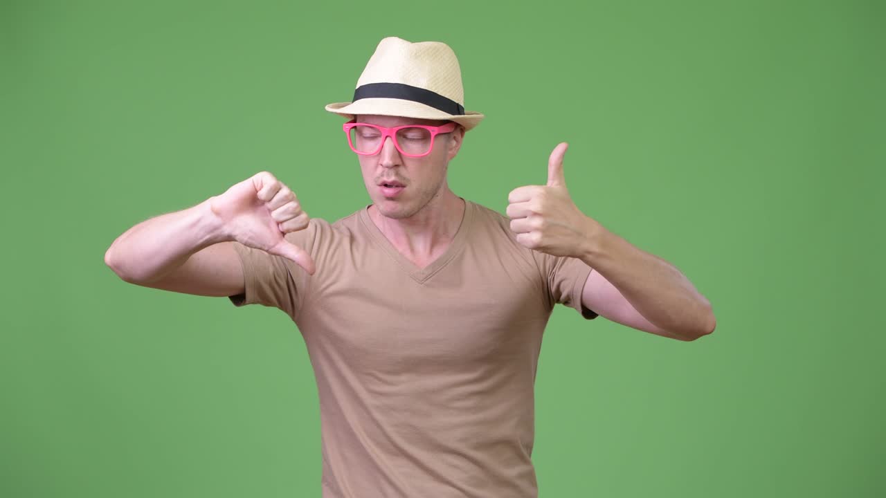 Young handsome tourist man choosing between thumbs up and thumbs down