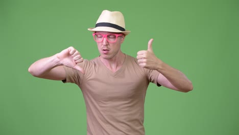 young handsome tourist man choosing between thumbs up and thumbs down