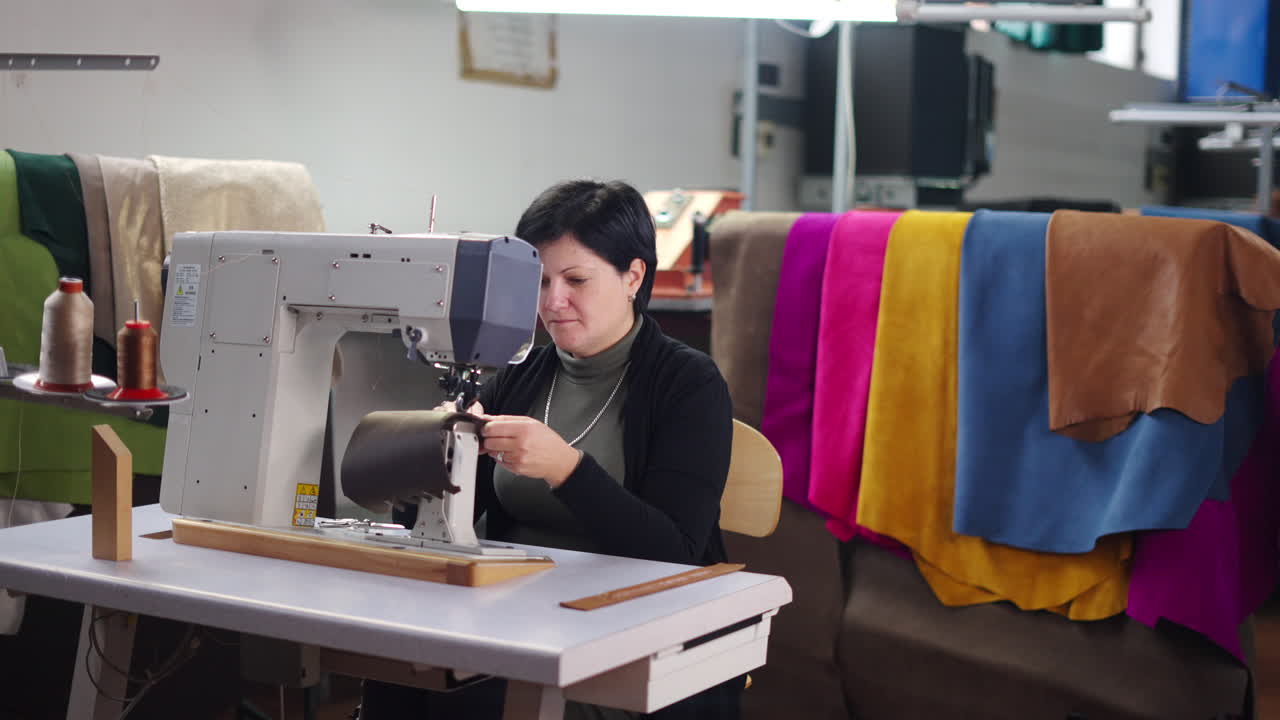 Woman sewing leather with a sewing machine in a workshop