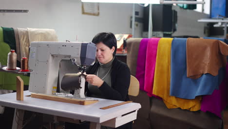 woman sewing leather with a sewing machine in a workshop