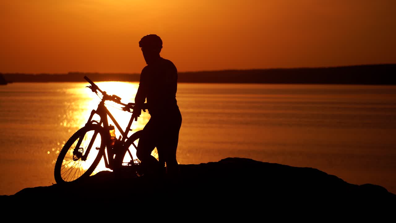 Rider resting on cycling trip in nature. Mountain biker looking at view on bike trail