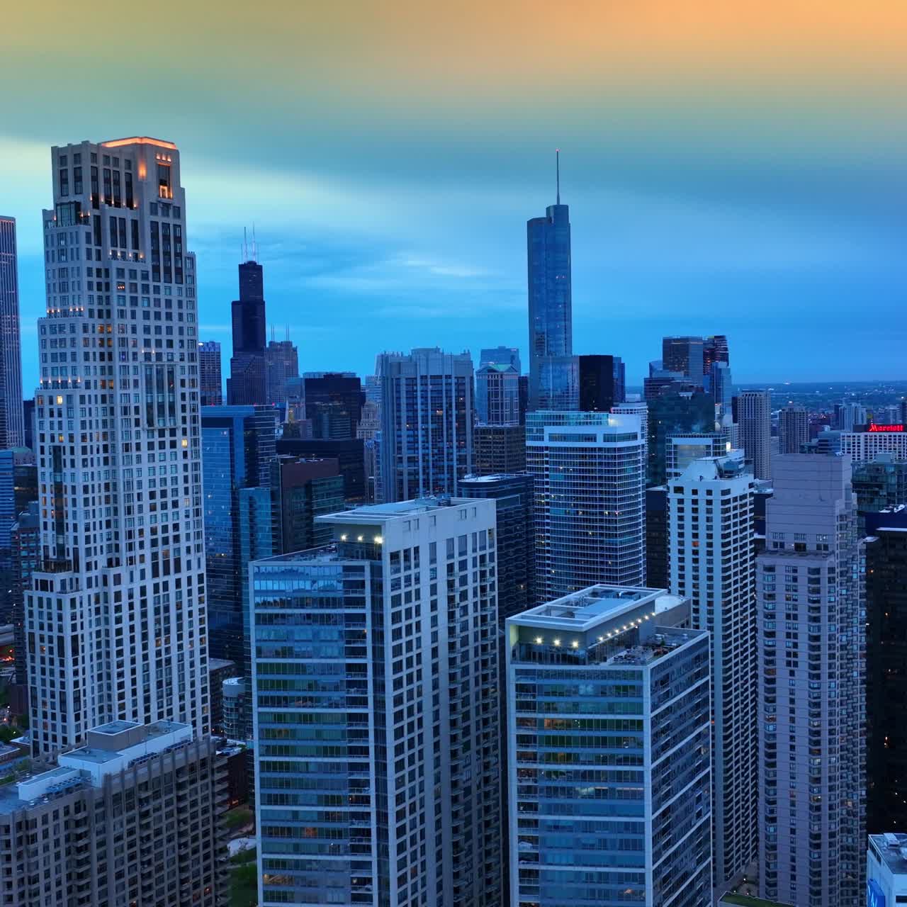 Chicago skyscrapers colored in blue in the evening time. Drone footage rising along the stunning skyscrapers at the background of beautiful sky at sun dusk
