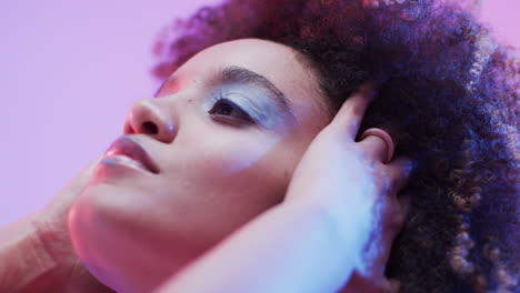 mujer biracial con cabello oscuro en luz azul y rosa, cámara lenta