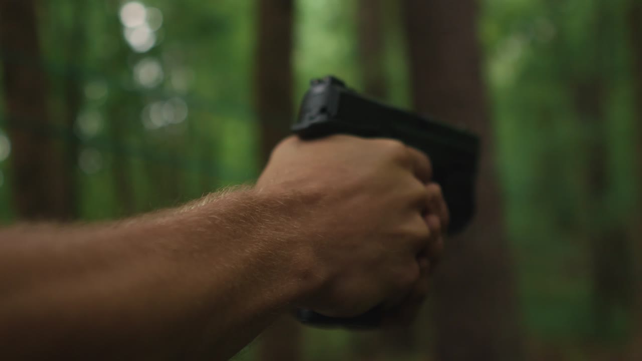 숲에서 총을 쏠 준비가 된 손에 총을 들고 있는 남자, 범죄의 복수 개념과 무기 공격을 찾고 있는 연쇄 살인범