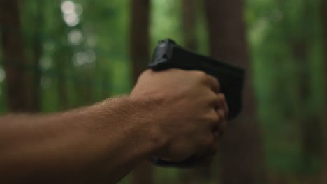 hombre sosteniendo una pistola lista para disparar en el bosque, asesino en serie buscando venganza concepto de crimen y asalto con armas de fuego