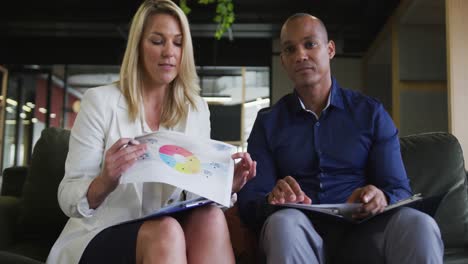 Two-diverse-business-colleagues-having-video-chat-and-discussing-paperwork-in-office