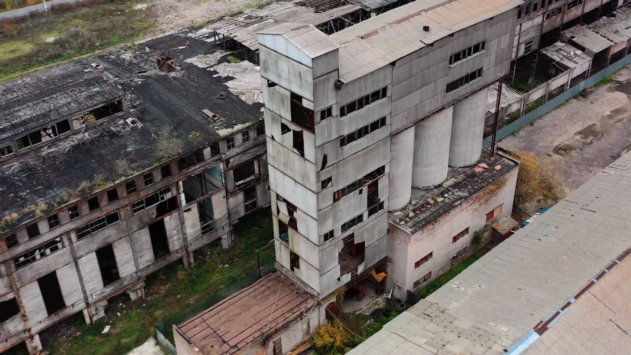 Ruined factory with damaged roof. Abandoned buildings on the field of military actions. Destroyed architecture. Aerial view.